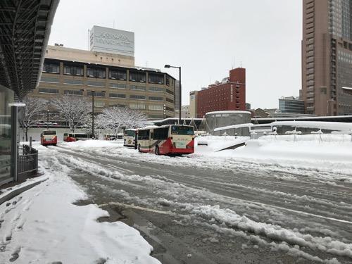 金沢駅東口のバス停留所前の雪景色とシャーベット状の道路