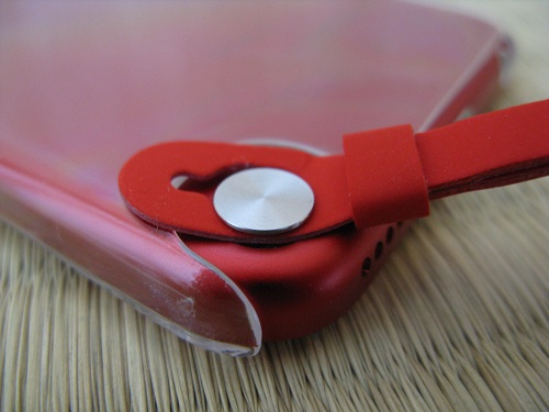 iPod touch 5本体のストラップ（loop）取り付け部分の銀色の円形ボタンの支柱に引っ掛けられたストラップ（loop）（装着途中）