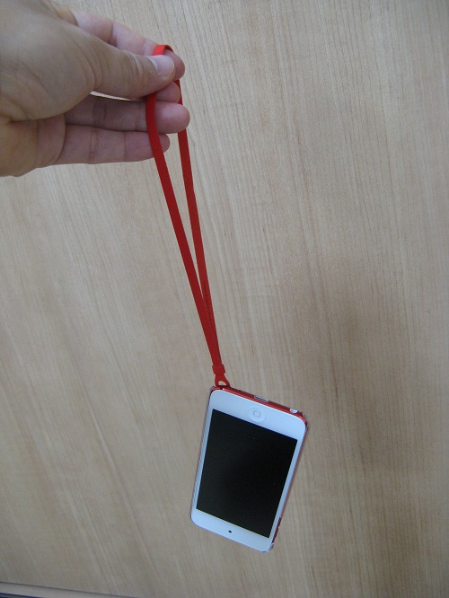 「iBUFFALO iPod touch（2012年発表モデル）専用 3Hハードケース iPod touch loop対応モデル 液晶保護フィルム付」の透明なハードケースを装着したiPod touch 5にストラップ（loop）取り付けて手にぶら下げた様子：iPod touch 5表面側