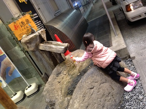 「天然温泉キスケのゆ」の新源泉のお湯をペットボトルに入れる娘