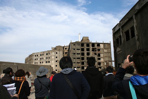 軍艦島の第三見学広場から31号棟（写真左）と30号棟（写真右）のアパートを眺める人々