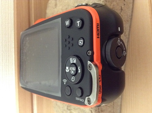 富士フィルムのデジタルカメラ「ファインピックス XP70（オレンジ）」本体（側面・バッテリー、SDメモリカード収納部）