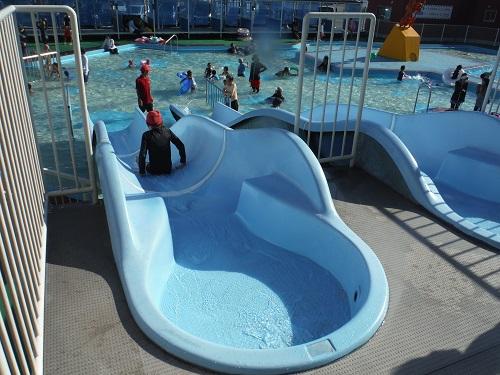 イヨテツスポーツセンターの幼児用プールのウォータースライダーを滑る小学6年生の娘