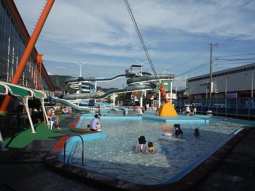 イヨテツスポーツセンターの屋外・幼児用プールと奥に見えるスパイラルウォータースライダー