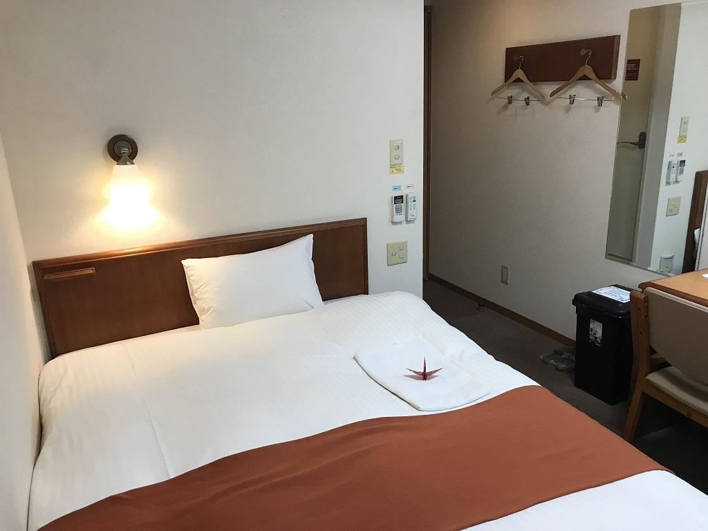 2020年2月 コモドホテル大分 禁煙シングルルーム 足元側から見たベッド、枕、壁のハンガー