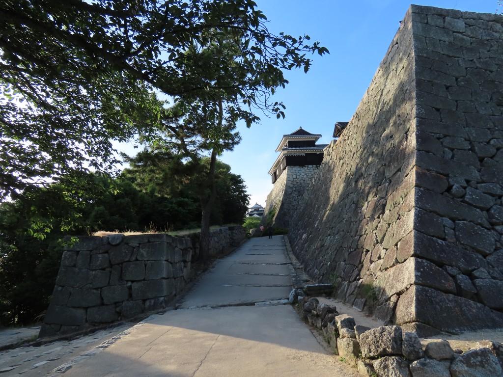 西日差す松山城の石垣、遠くに見える天守閣