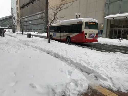 ドーミーイン金沢前の歩道を覆う雪と去りゆく路線バス