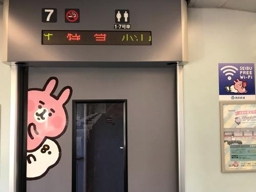 西武新宿駅2番線ホームに停車中の「カナヘイの小動物 ゆるっと小旅 西武鉄道で行く川越旅」のラッピング列車(7号車デッキへの自動ドアとSEIBU FREE Wi-Fiのシールのピンクのうさぎ、ピスケ)