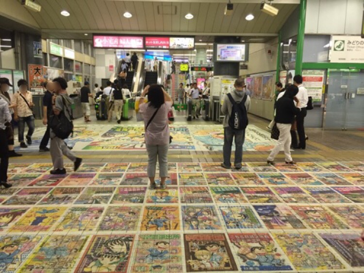 JR亀有駅改札口前の床に貼られたこち亀コミックスの表紙集