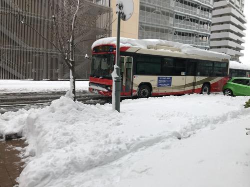 ドーミーイン金沢の出入口前の雪景色と路線バス