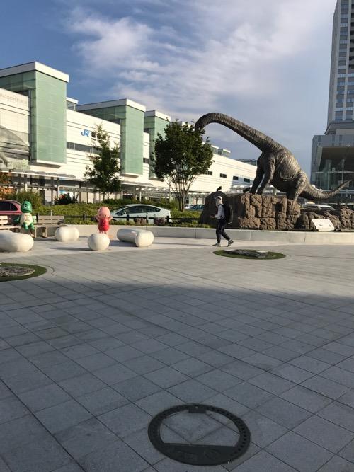 福井県福井市の「げすい」と書かれた周辺の道の石模様が付いたマンホールの蓋の周囲の様子 - JR福井駅西口駅前広場の恐竜など