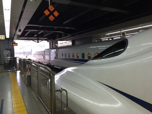 品川駅新幹線ホームに停車しつつある新幹線のぞみ25号博多行の先頭車両・進行方向側