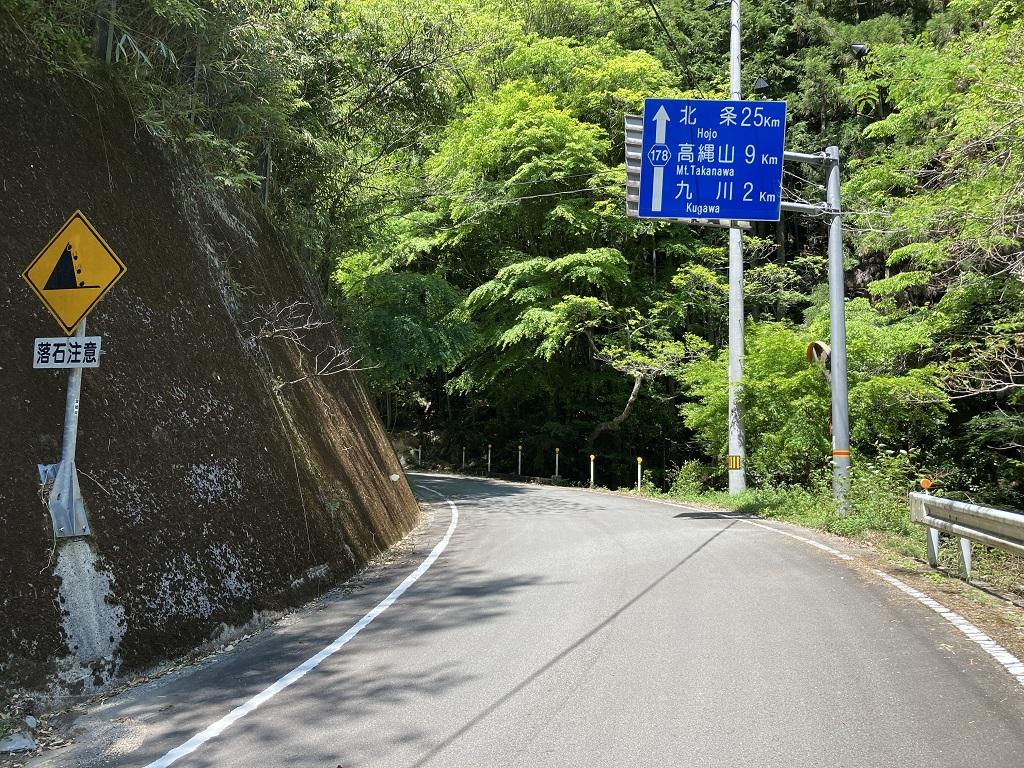 高縄山入口の道路標識「落石注意」「北条 25km、高縄山 9km、九川 2km」