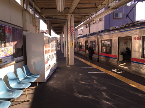 京成金町駅ホームの青い椅子、自動販売機、停車中の電車