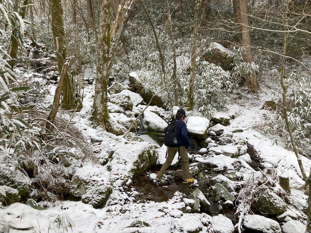 皿ヶ嶺畑野川ルート12：雪景色の中、小川を渡る娘