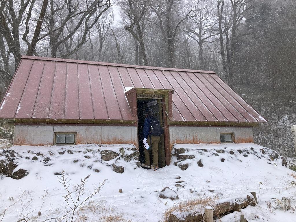 皿ヶ嶺 竜神平4：吹雪の中、竜神平の山小屋の扉を開けて中に入ろうとする娘