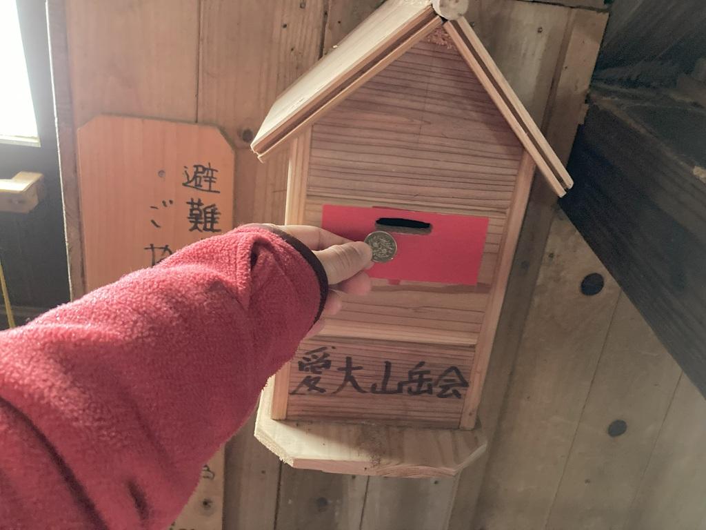 皿ヶ嶺 竜神平9：竜神平の山小屋の中にある愛大山岳会の料金箱に100円を投入する直前