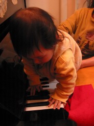 ピアノの鍵盤の上をハイハイする0歳児の娘
