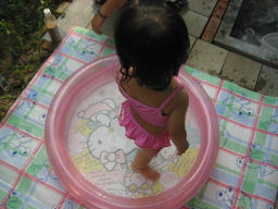 ピンクの水着（しかもビキニ！）を着て実家の庭に置いたビニールプールで水遊びをする娘